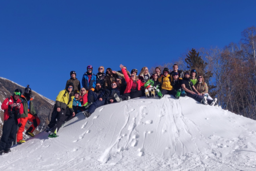 people in winter sports outfits sitting on a snowy hill